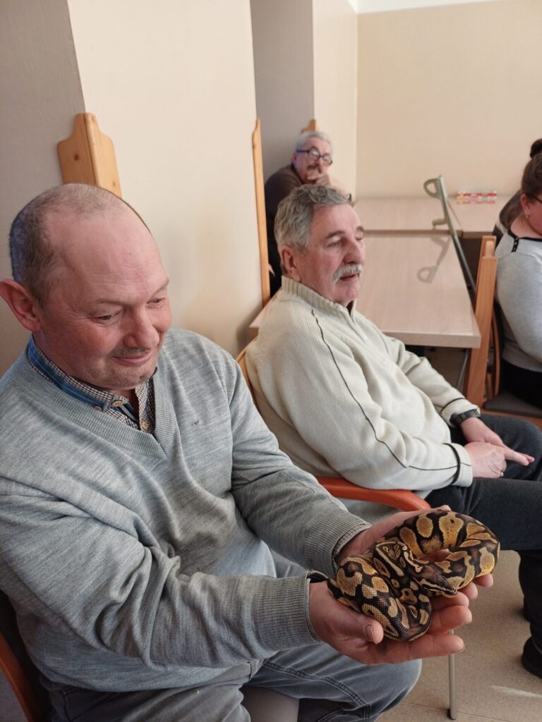Podopieczny ŚDS trzyma w rękach węża
