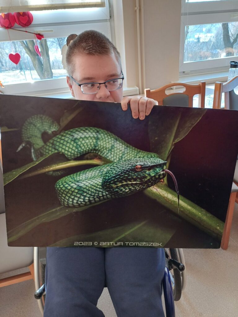 Podopieczna ŚDS trzyma w rękach tablicę przedstawiającą węża