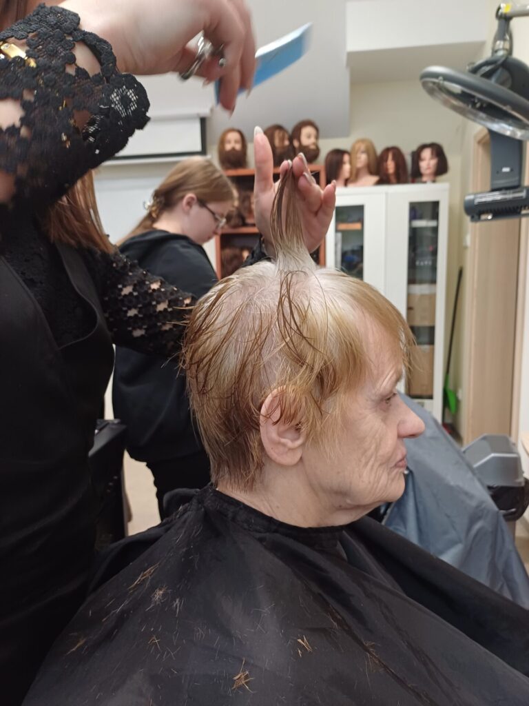 Podopieczna ŚDS ma strzyżone włosy przez uczennicę klasy fryzjerskiej Zespołu Szkół w Gdowie