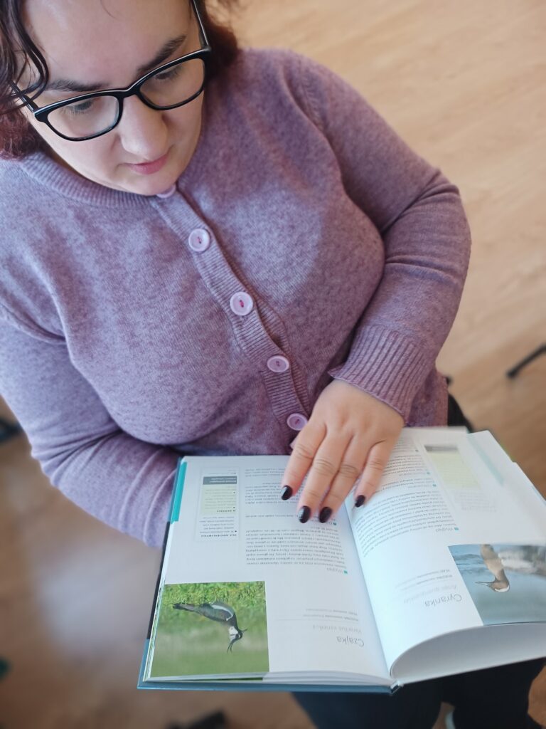 Podopieczna ŚDS przegląda atlas o ptakach