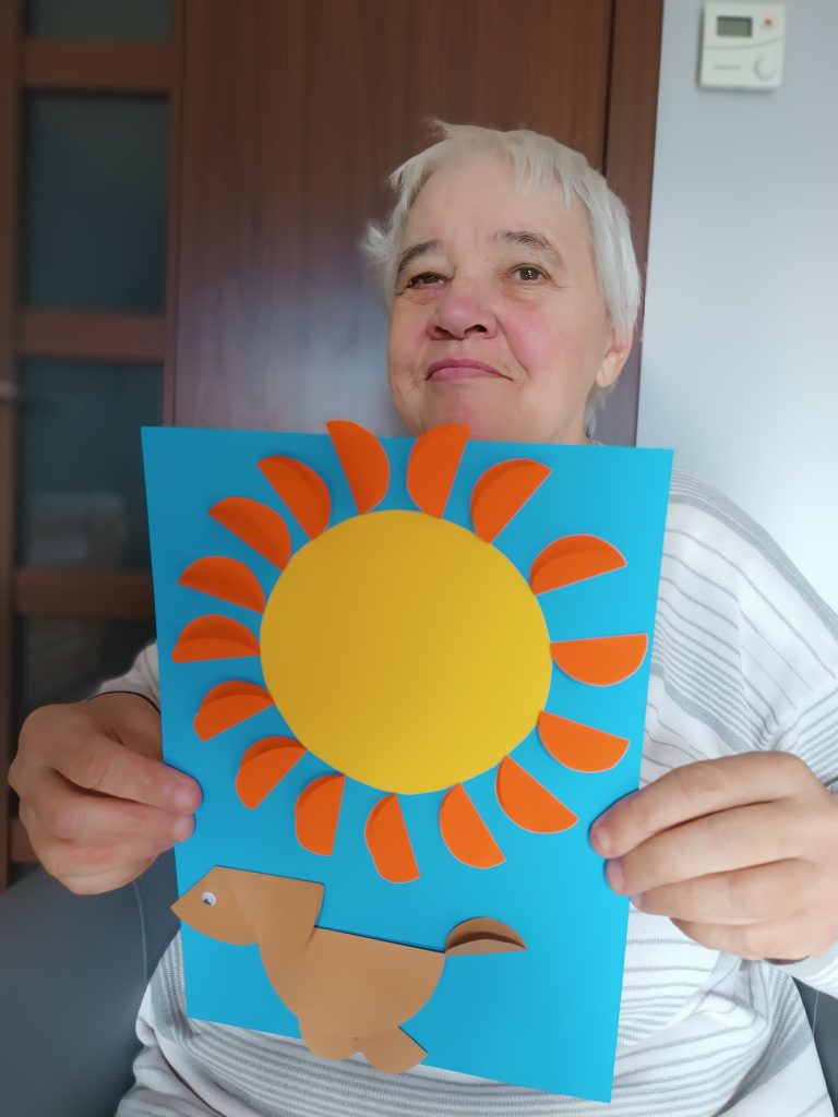 Podopieczna pokazuje swoją pracę plastyczną