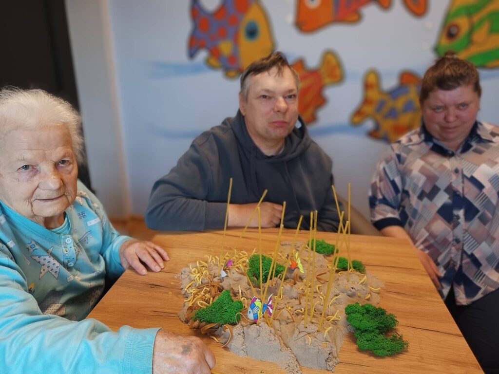 podopieczni prezentują makietę rafy koralowej przygotowaną podczas zajęć terapeutycznych