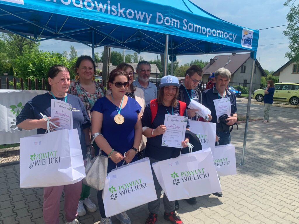 Grupa uczestników pozuje do zdjęcia z dyplomami i upominkami