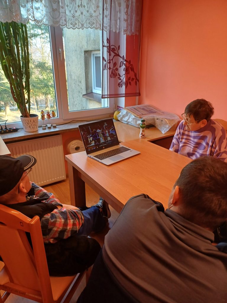 grupa podopiecznych ogląda film edukacyjny na laptopie