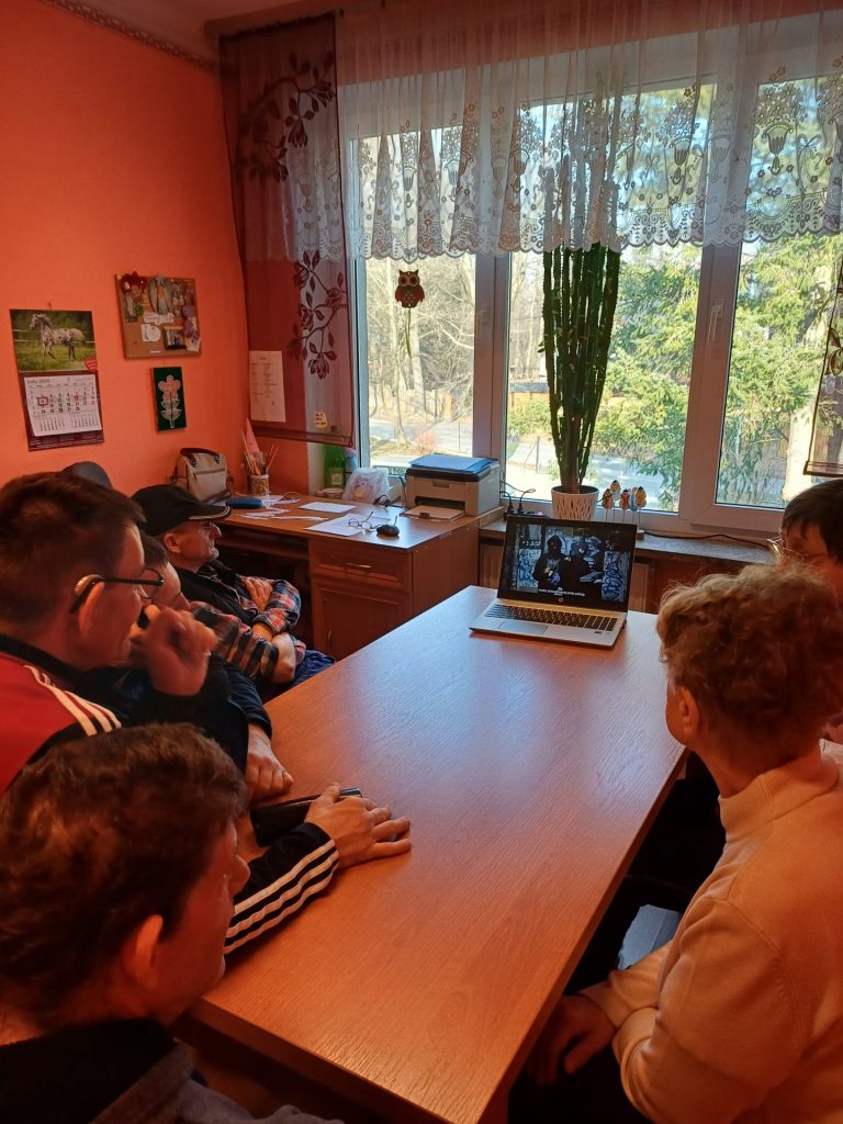 grupa podopiecznych ogląda film edukacyjny na laptopie