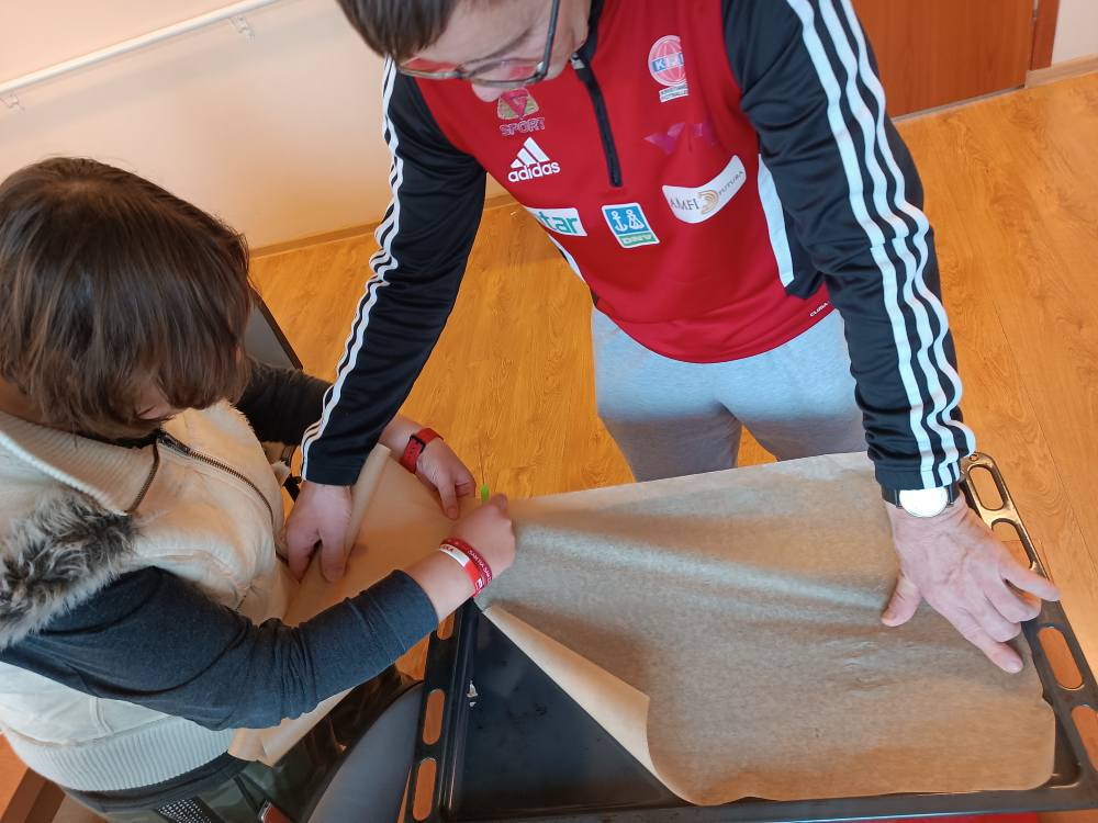 Podopieczni przygotowują brytfannę do pieczenia ciastek