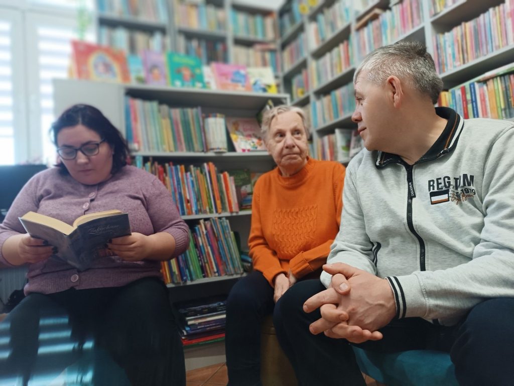 Grupa Podopiecznych czyta książki w bibliotece
