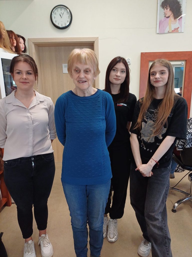 Uczennice klasy fryzjerskiej prezentują swoją pracę wraz z modelką (Podopieczną)