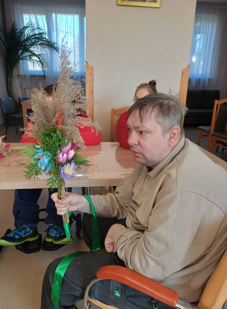 Podopieczny prezentuje wykonaną przez siebie palmę wielkanocną