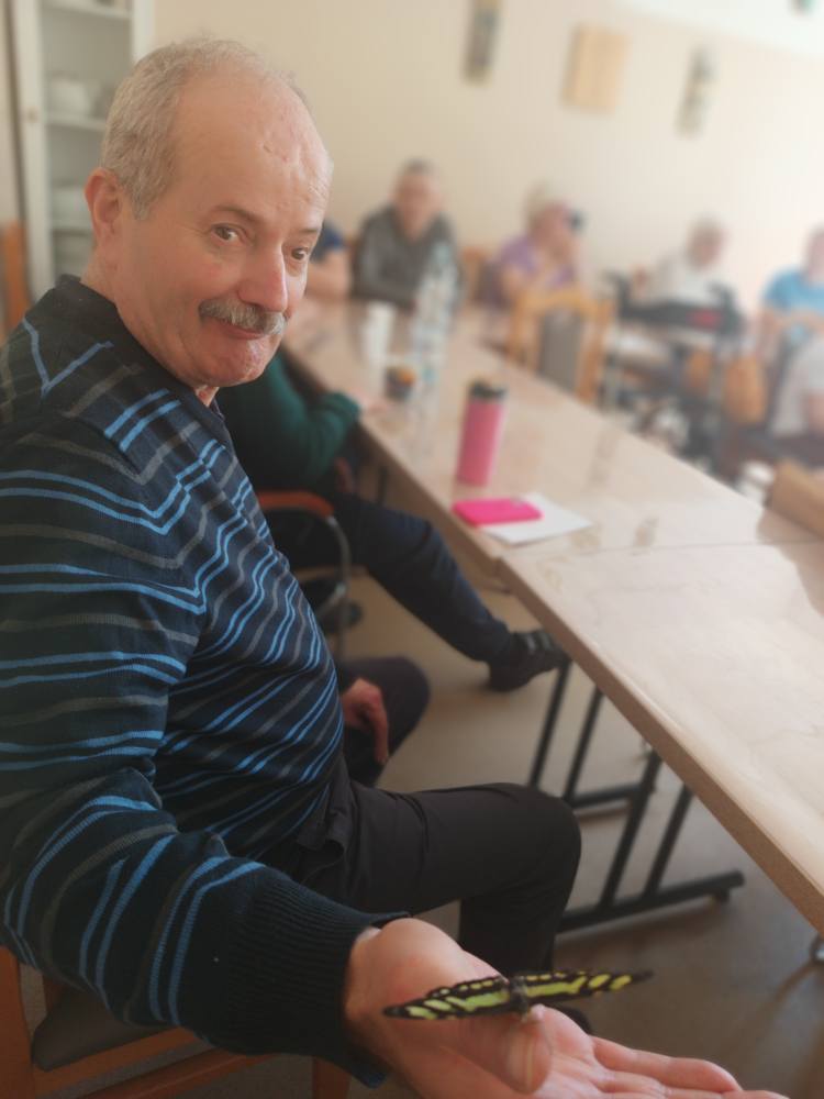 Podopieczny trzyma motyla na dłoni