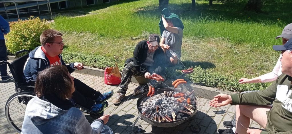 Podopieczni smażą kiełbaski na ognisku