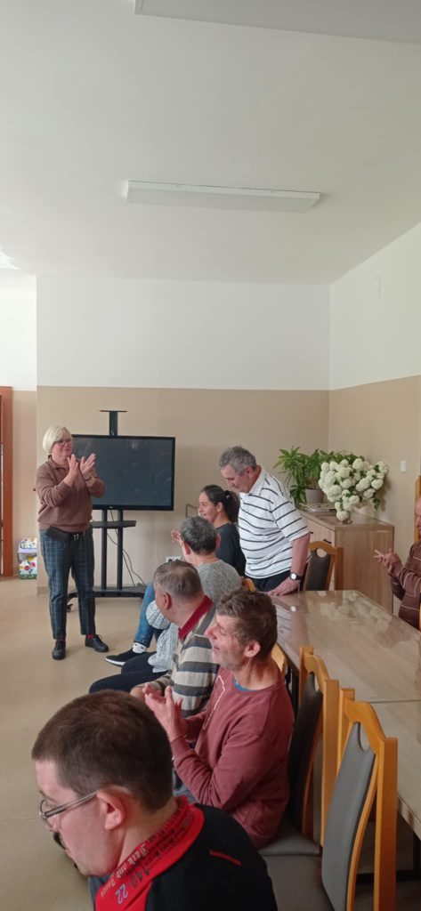 Podopieczni wykonują proste ćwiczenia fizyczne pod przewodnictwem terapeutów