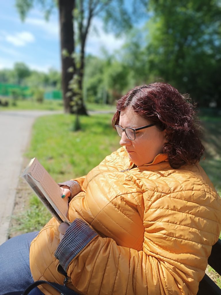 Podopieczna czyta książkę na ławce w parku