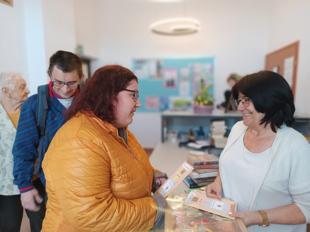 Podopieczni wręczają prezenty pani bibliotekarce