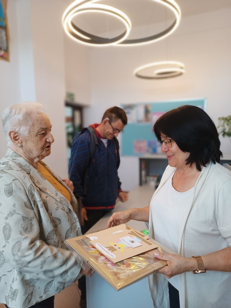 Podopieczni wręczają prezenty pani bibliotekarce