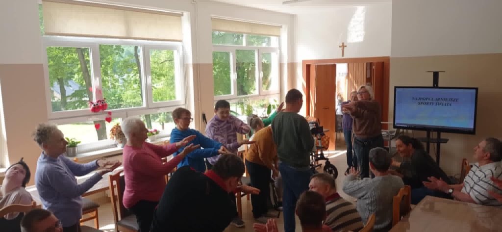 Podopieczni wykonują proste ćwiczenia fizyczne pod przewodnictwem terapeutów