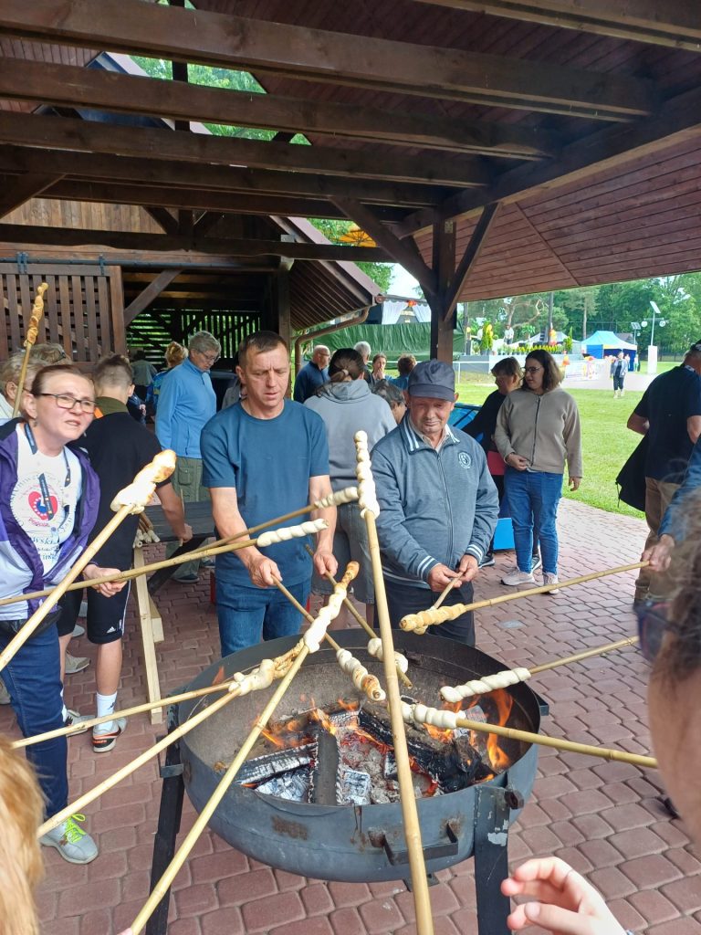 grupa uczestników festiwalu piecze świderki na ognisku