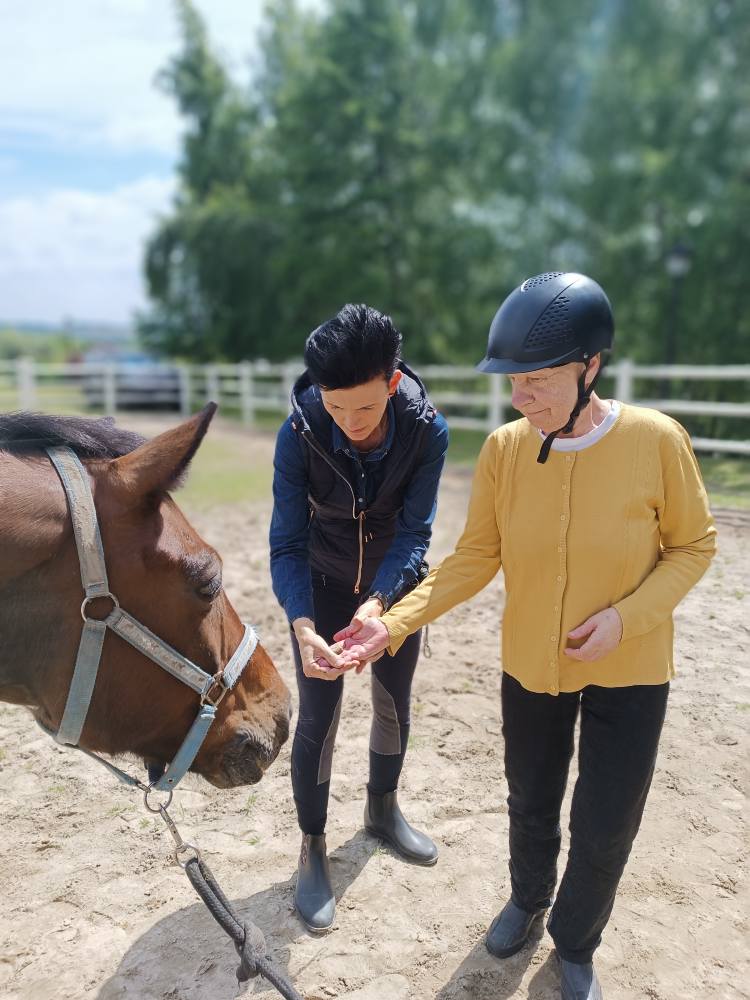 instruktorka przygotowuje podopieczną do karmienia konia