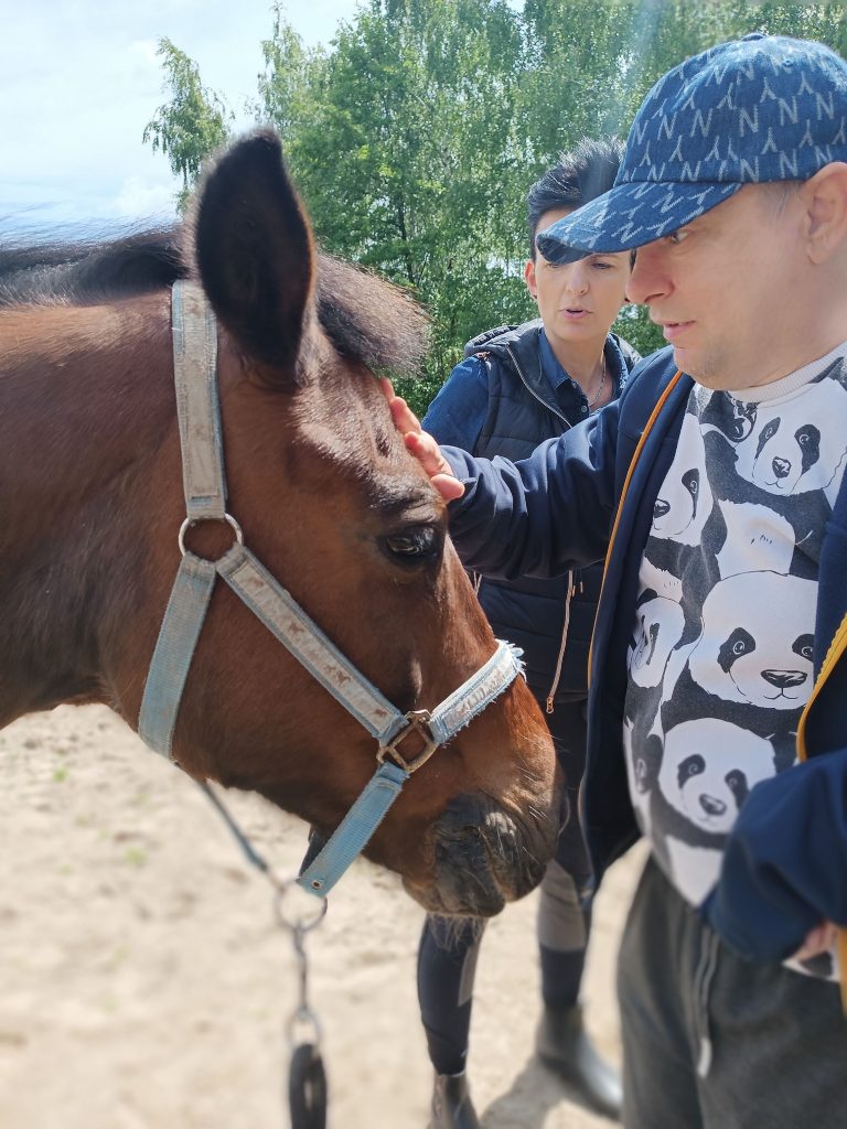 podopieczny głaszcze konia po głowie