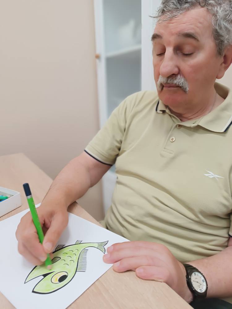 Podopieczny koloruje obrazek ryby