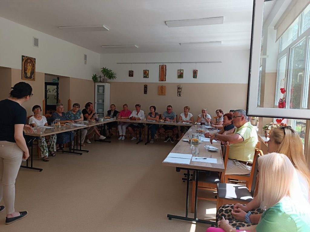 Grupa osób słucha prelekcji
