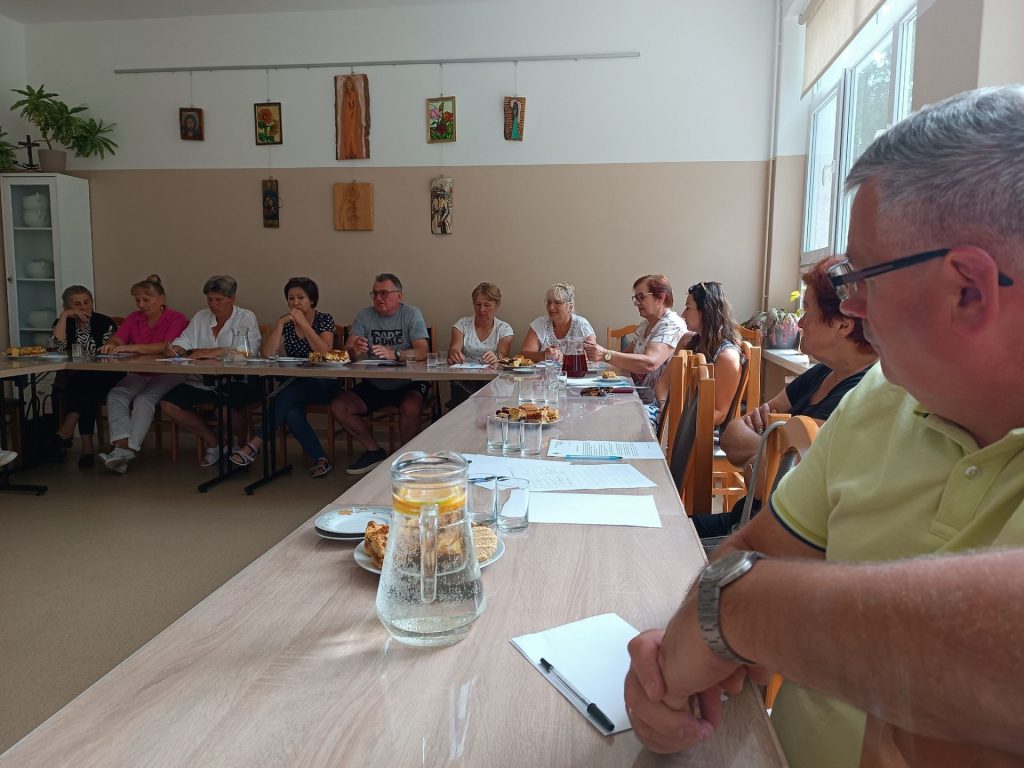 Grupa osób słucha prelekcji
