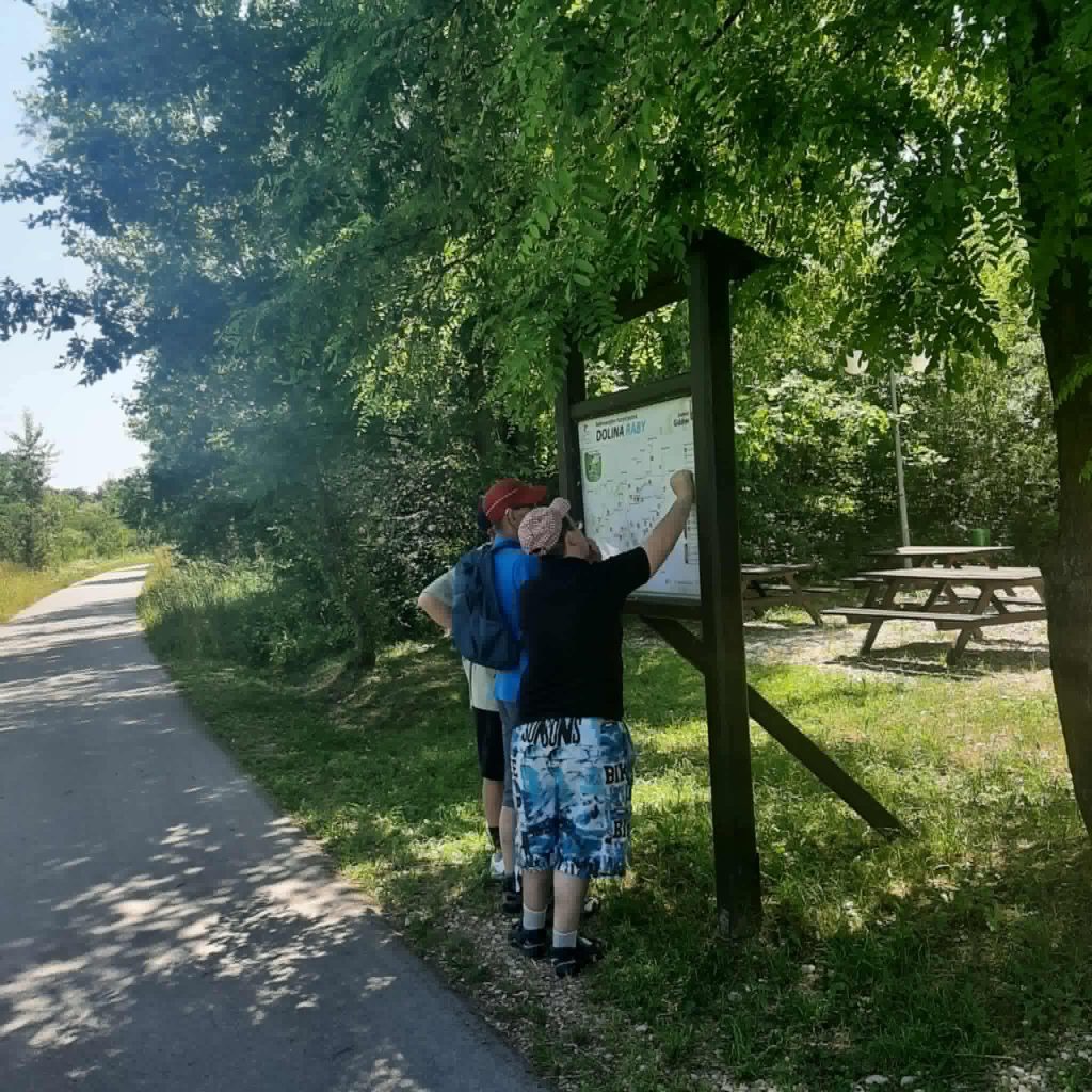 Podopieczni czytają przydrożną tablicę informacyjną
