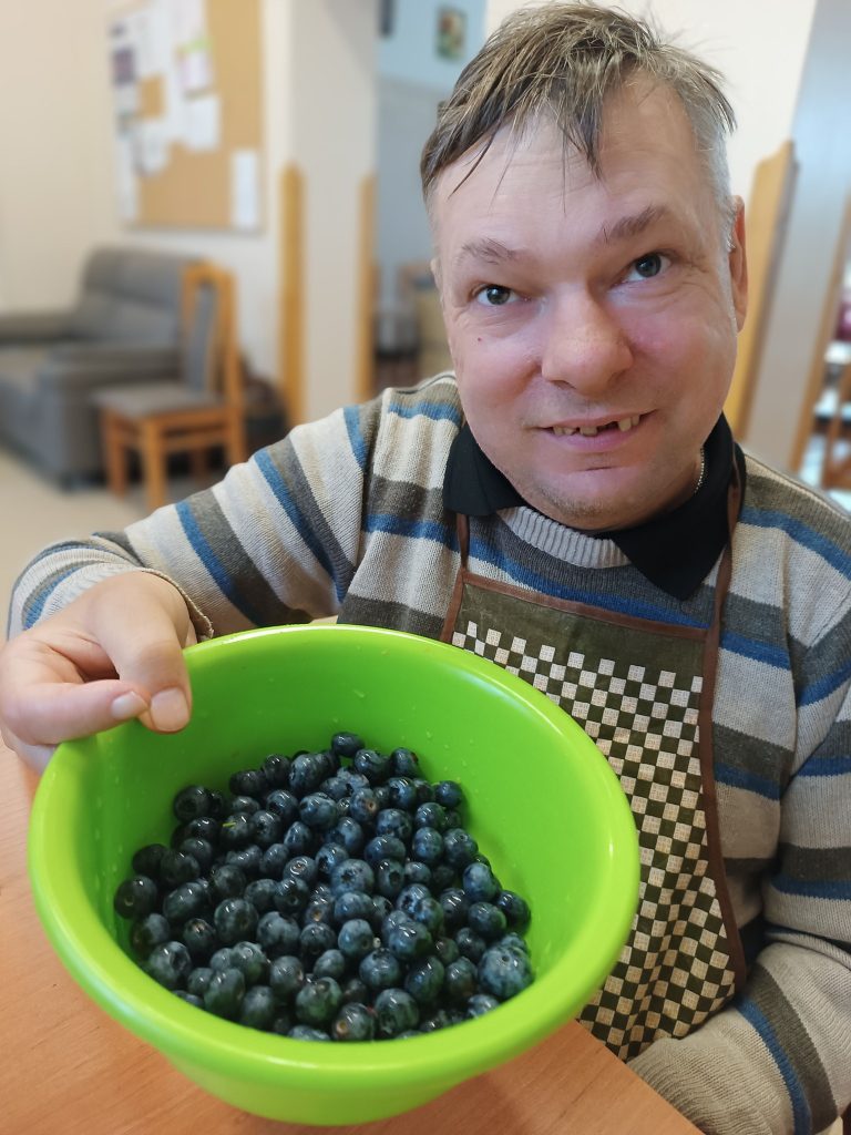 Podopieczny trzyma miskę z borówkami