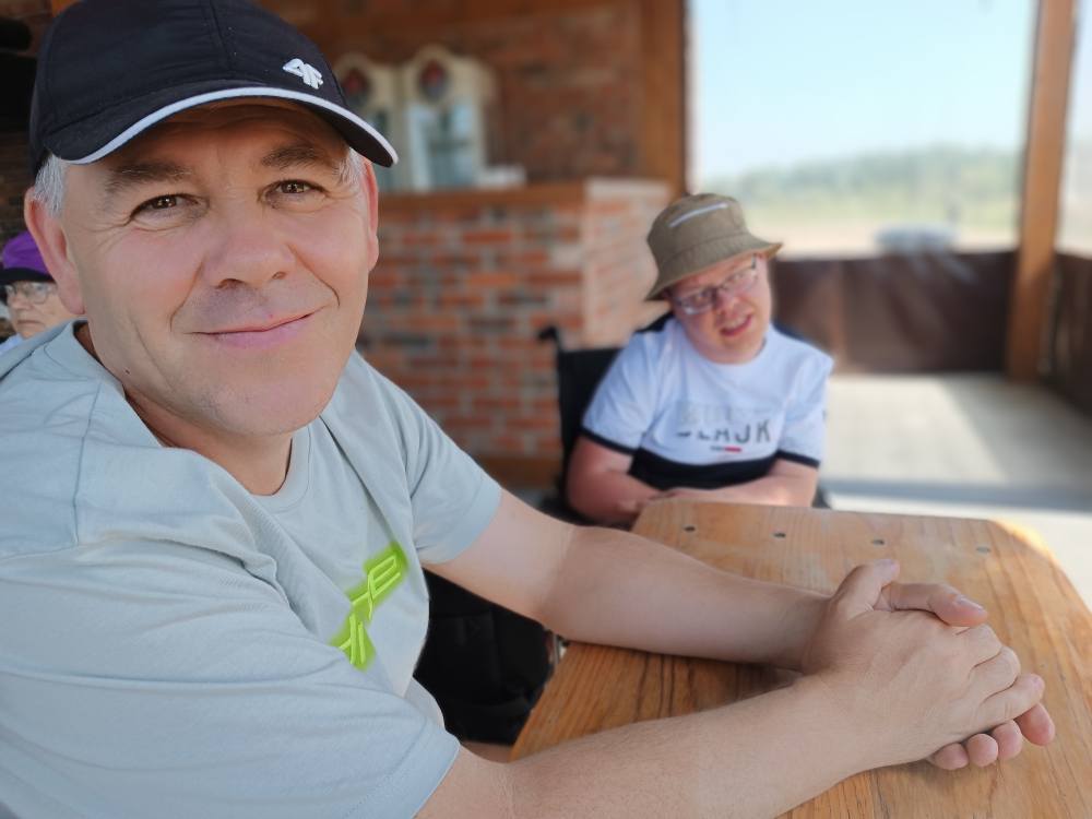 Podopieczni siedzą pod wiatą wypoczynkową