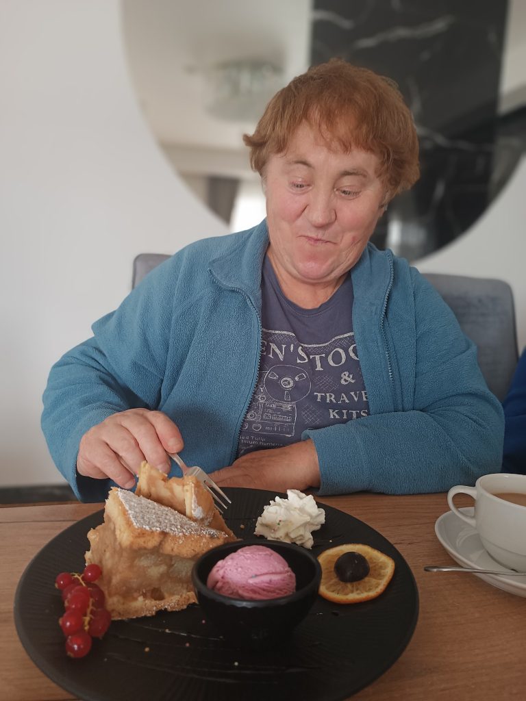 Podopieczna degustuje ciasto w kawiarni