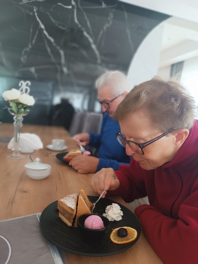 Podopieczni piją kawę i jedzą ciasto w restauracji