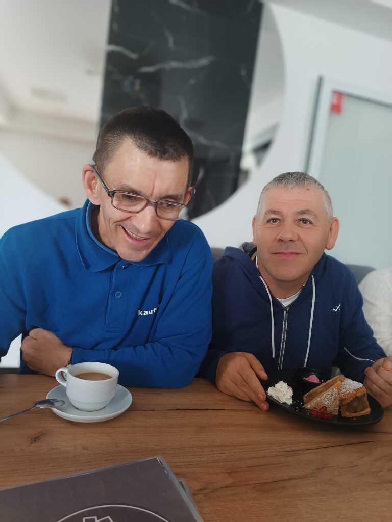 Podopieczni piją kawę i jedzą ciasto w restauracji