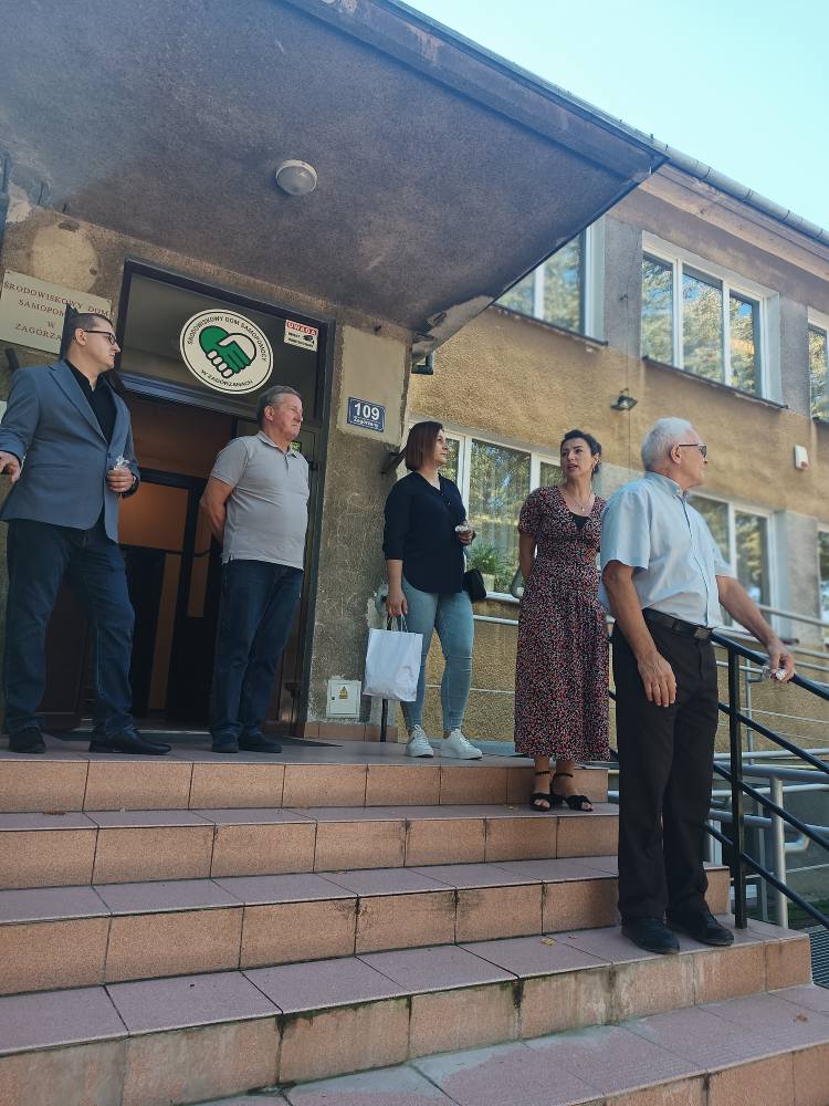 przedstawiciele Rady Gminy stoją przed budynkiem ŚDS