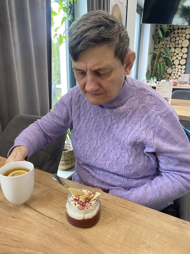 Podopieczna je deser i popija kawę w restauracji