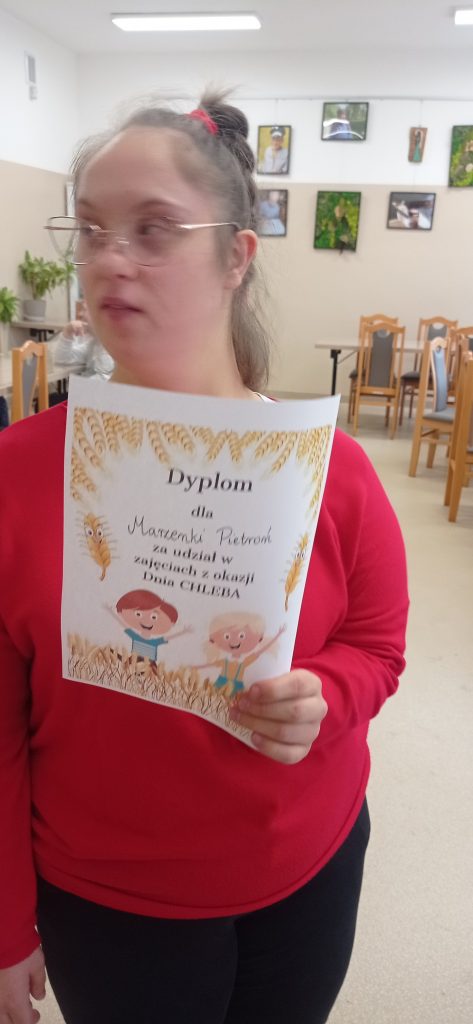 Podopieczna trzyma dyplom za udział w Dniu Chleba