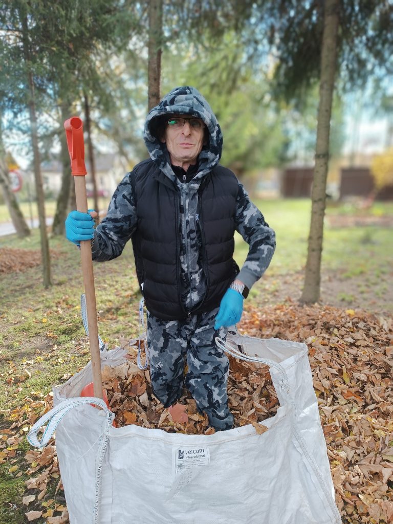 Podopieczny wrzuca liście do big baga