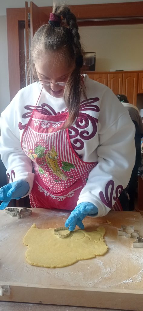 Podopieczna wykrawa ciasteczko z rozwałkowanego ciasta