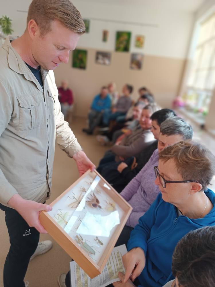 prowadzący spotkanie pokazuje gablotę z zasuszonymi owadami
