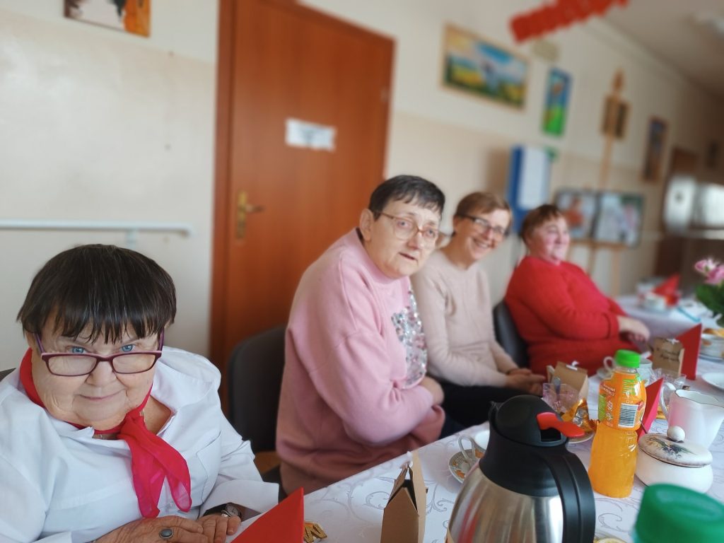 podopieczni siedzą wspólnie przy stole podczas spotkania z okazji Dnia Seniora