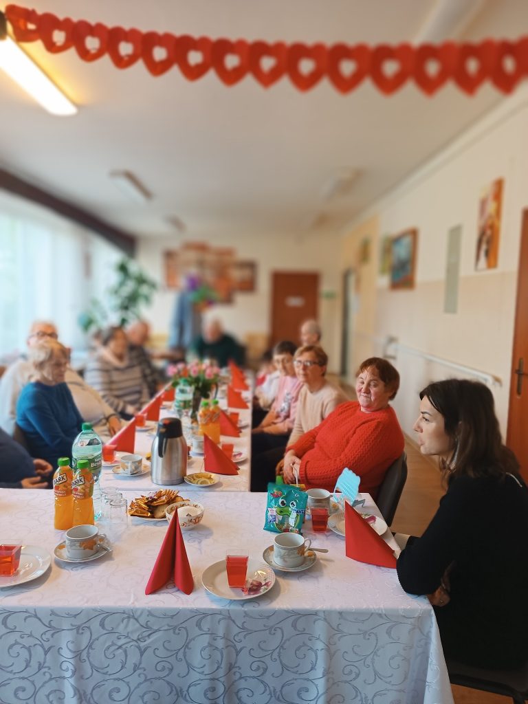 podopieczni siedzą wspólnie przy stole podczas spotkania z okazji Dnia Seniora