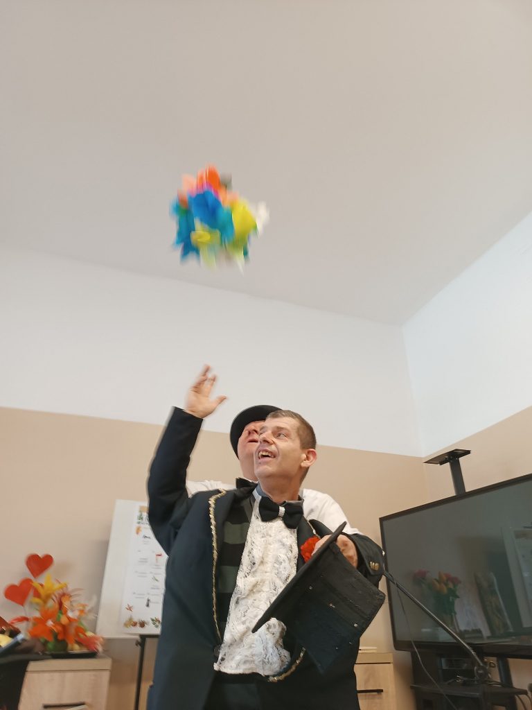 Iluzjonista wykonuje sztuczkę przy udziale podopiecznego