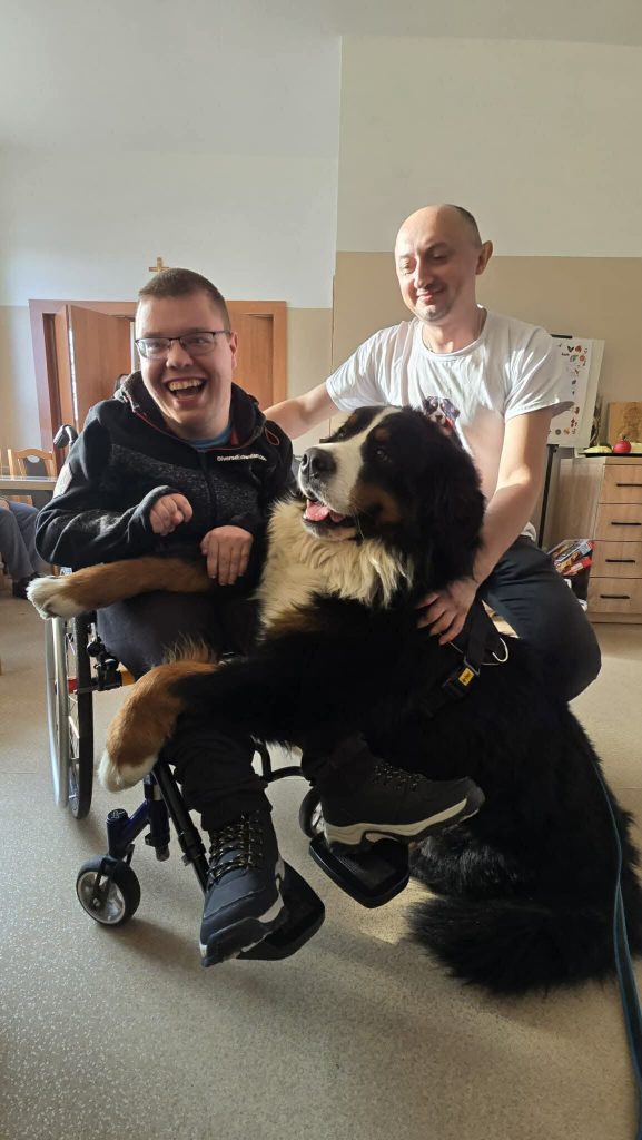 Podopieczny pozuje do zdjęcia z psem i jego opiekunem