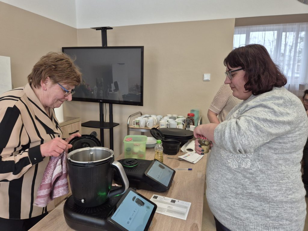 Podopieczna wraz z prowadzącą pokaz przygotowuje ciasto na bułeczki