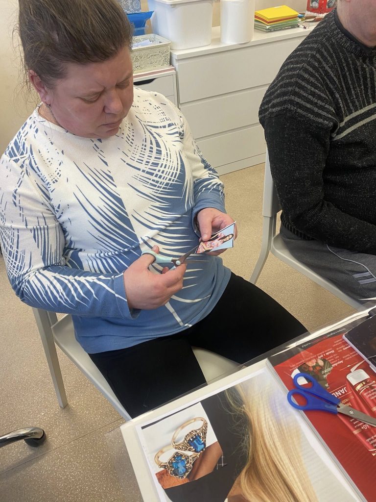 podopieczna przygotowuje kolaż wycinków z gazet