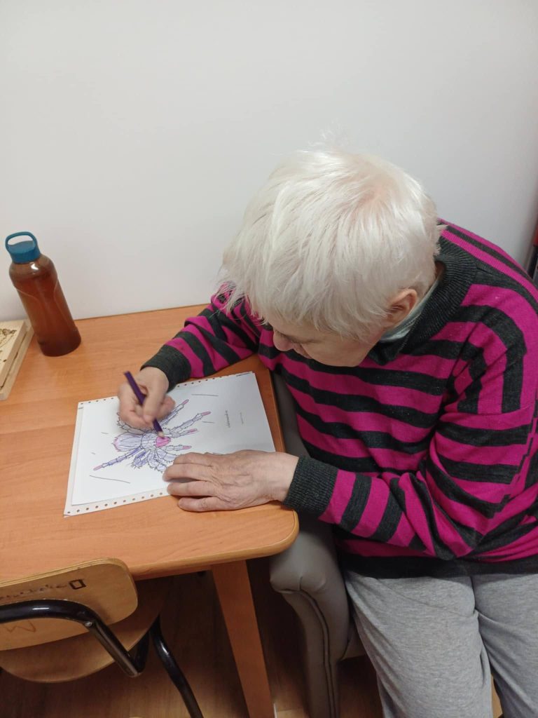 Podopieczna koloruje kredkami obrazek