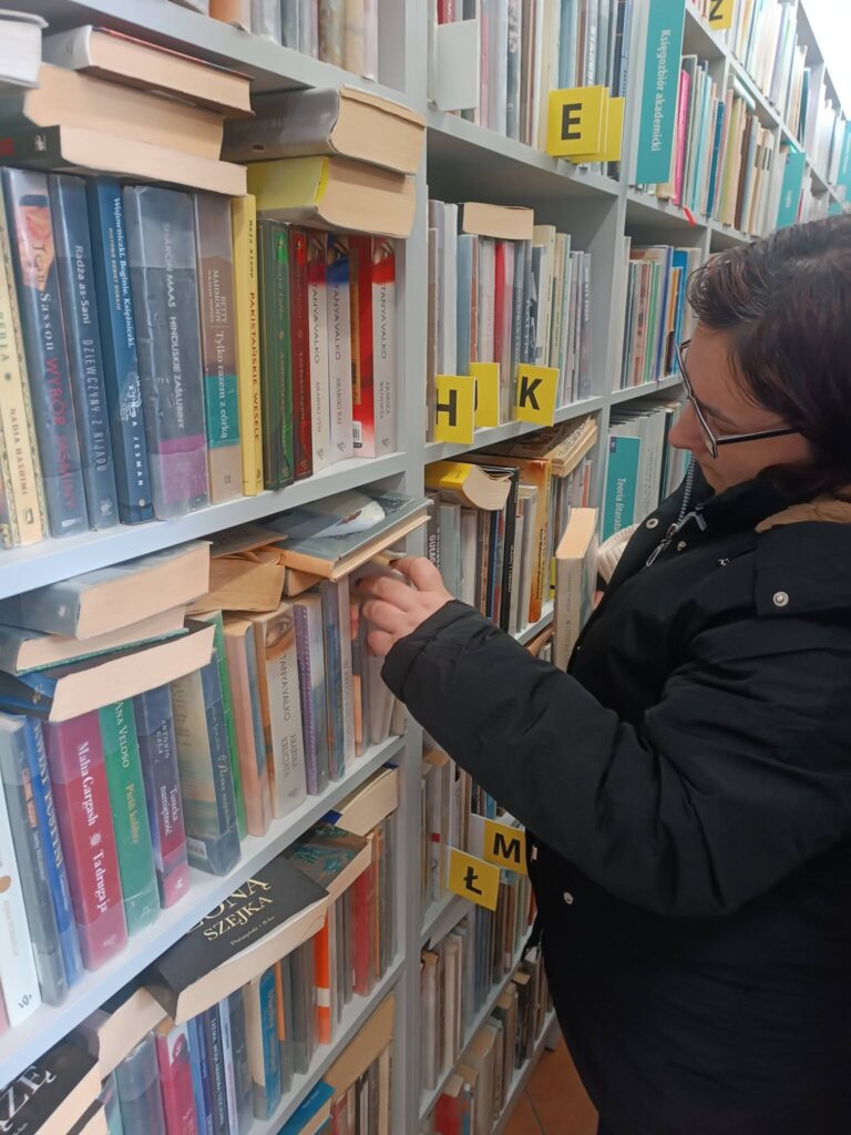Podopieczna przegląda zbiory biblioteczne