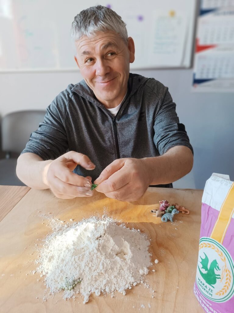 Podopieczny poszukuje figurek dinozaurów w stercie mąki