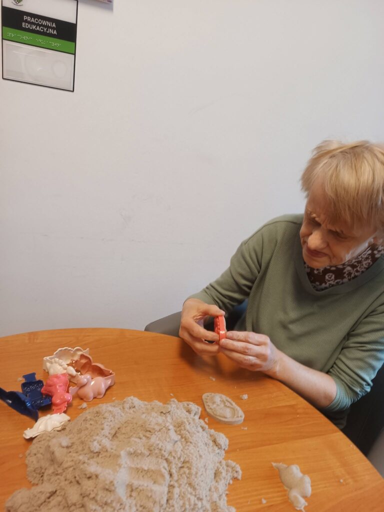 Podopieczna odbija kształty w piasku kinetycznym