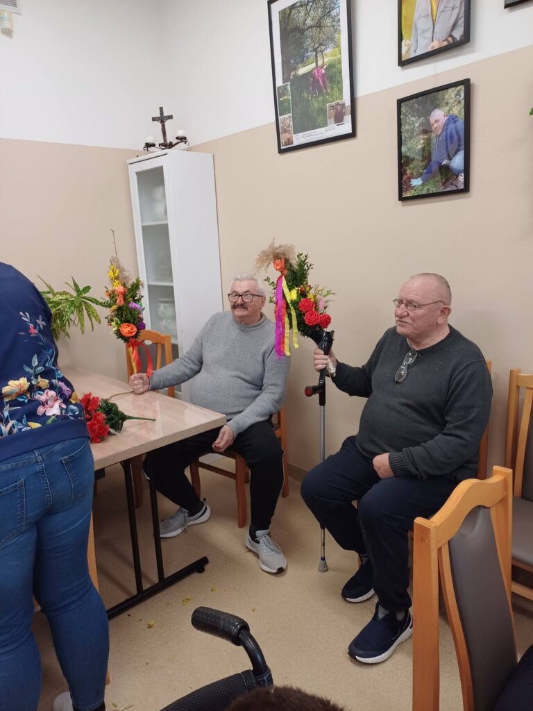 podopieczni trzymają w dłoniach palmy wykonane podczas warsztatów