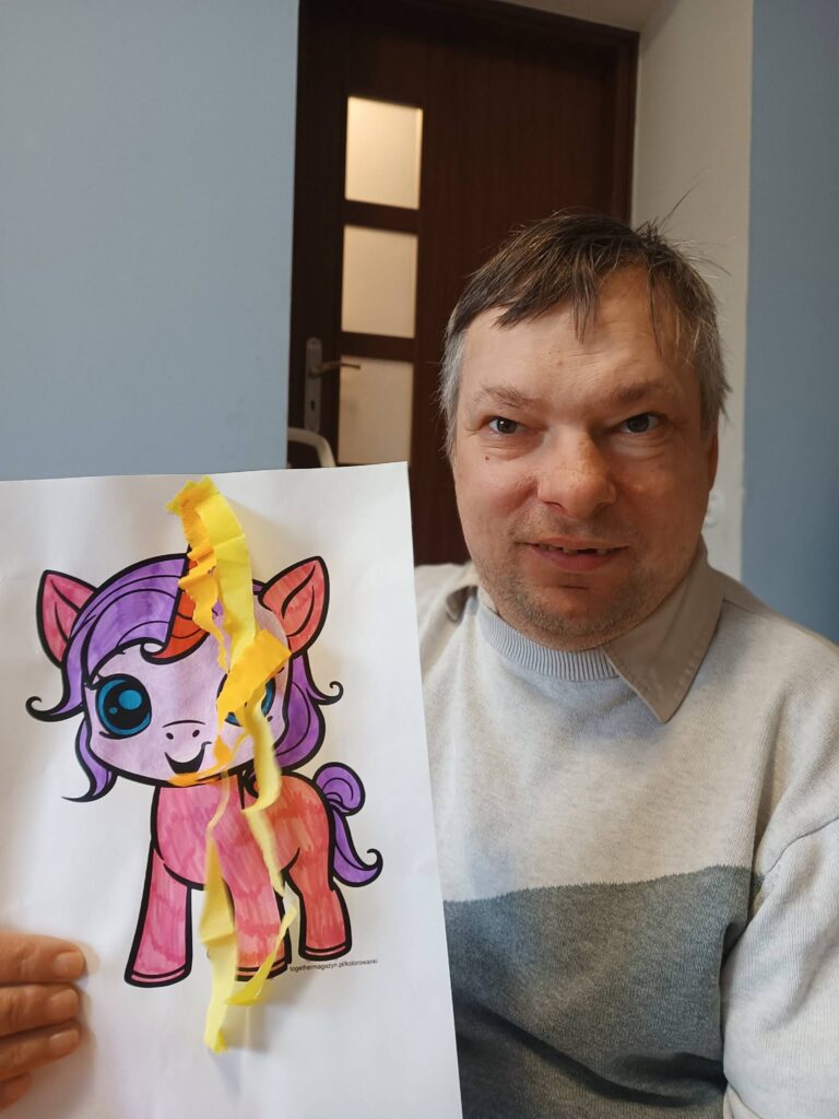 podopieczny pokazuje wykonany przez siebie obrazek